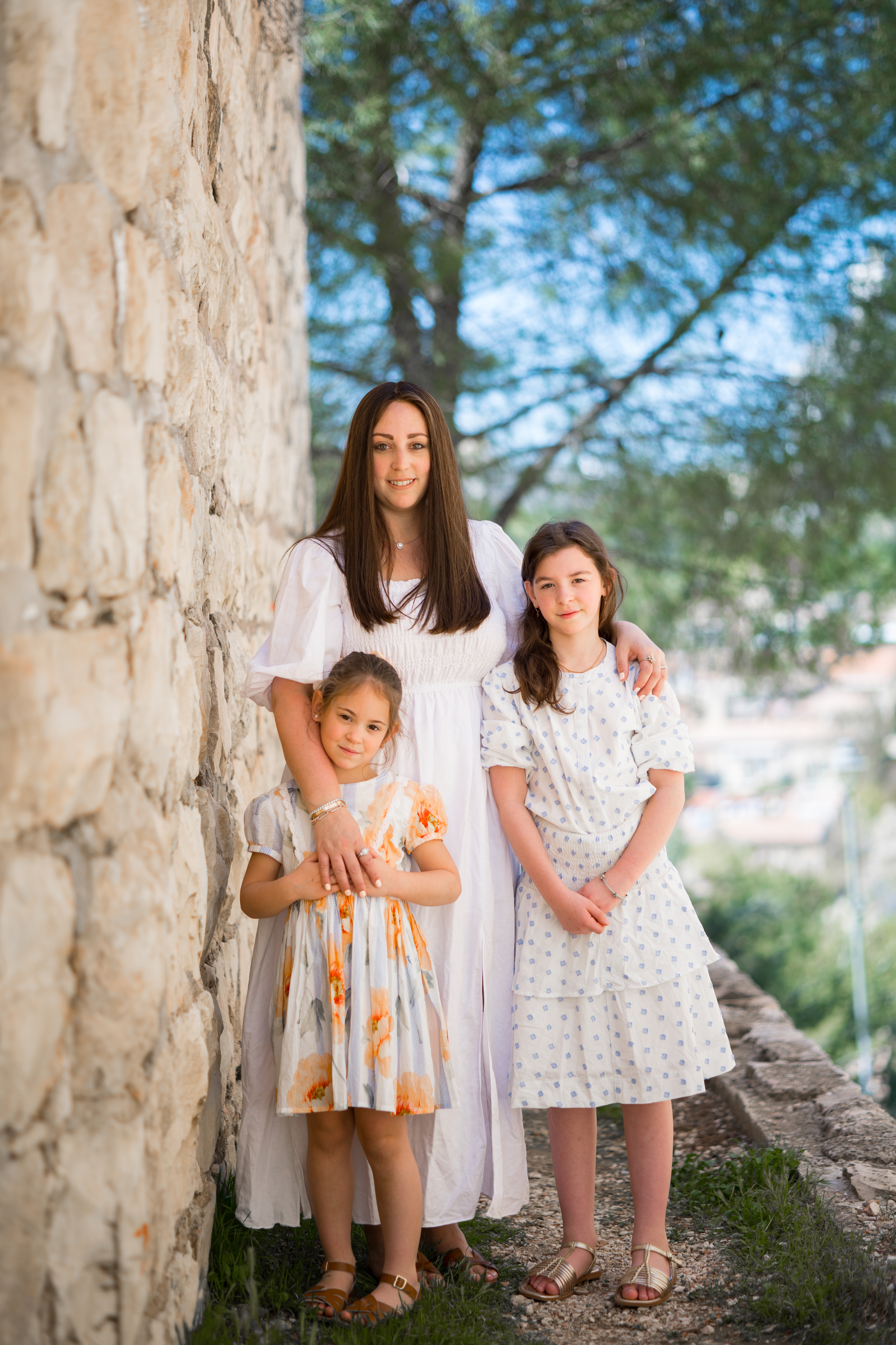 A mother with her daughters beside a stone wall