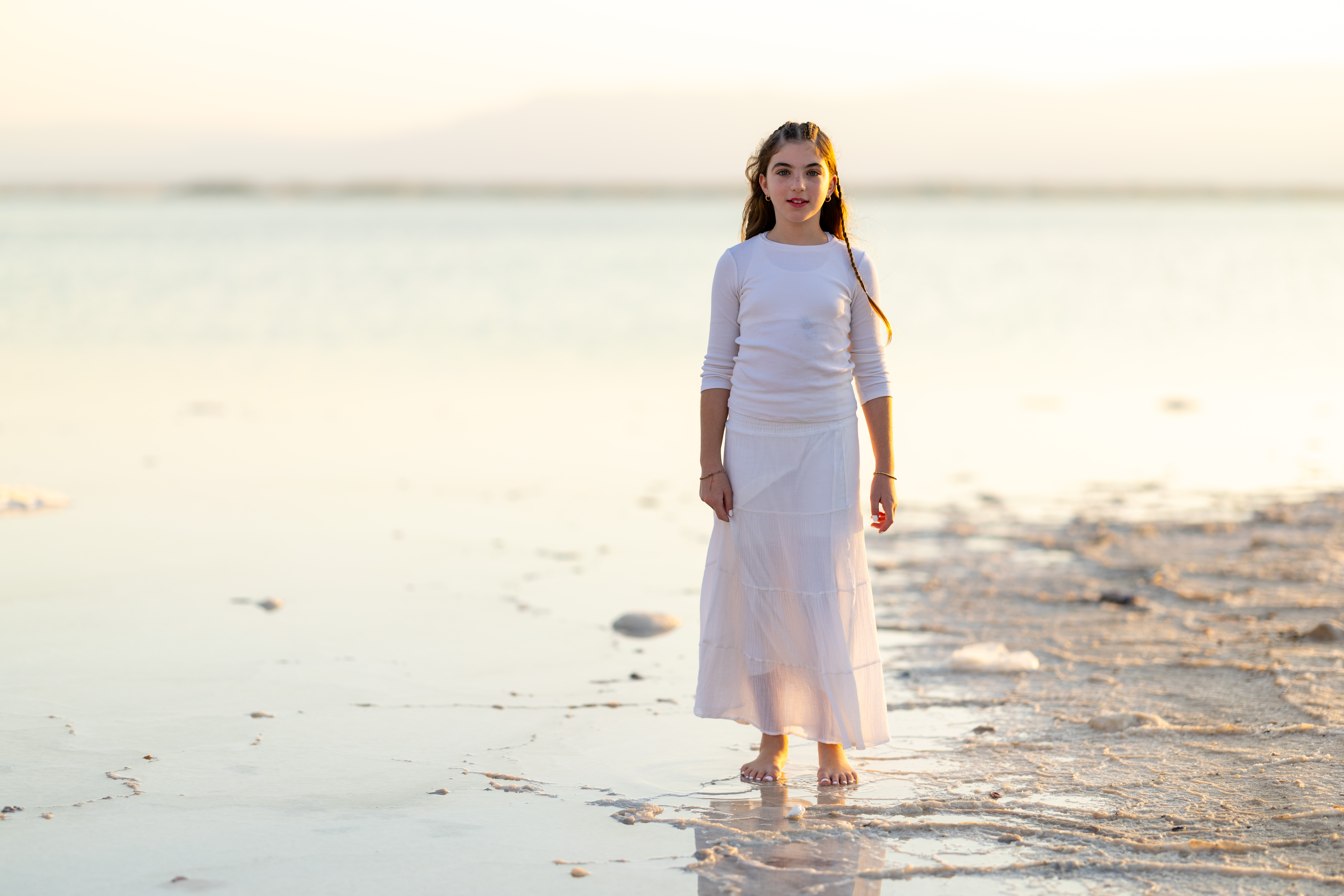 A young girl by the water at sunset