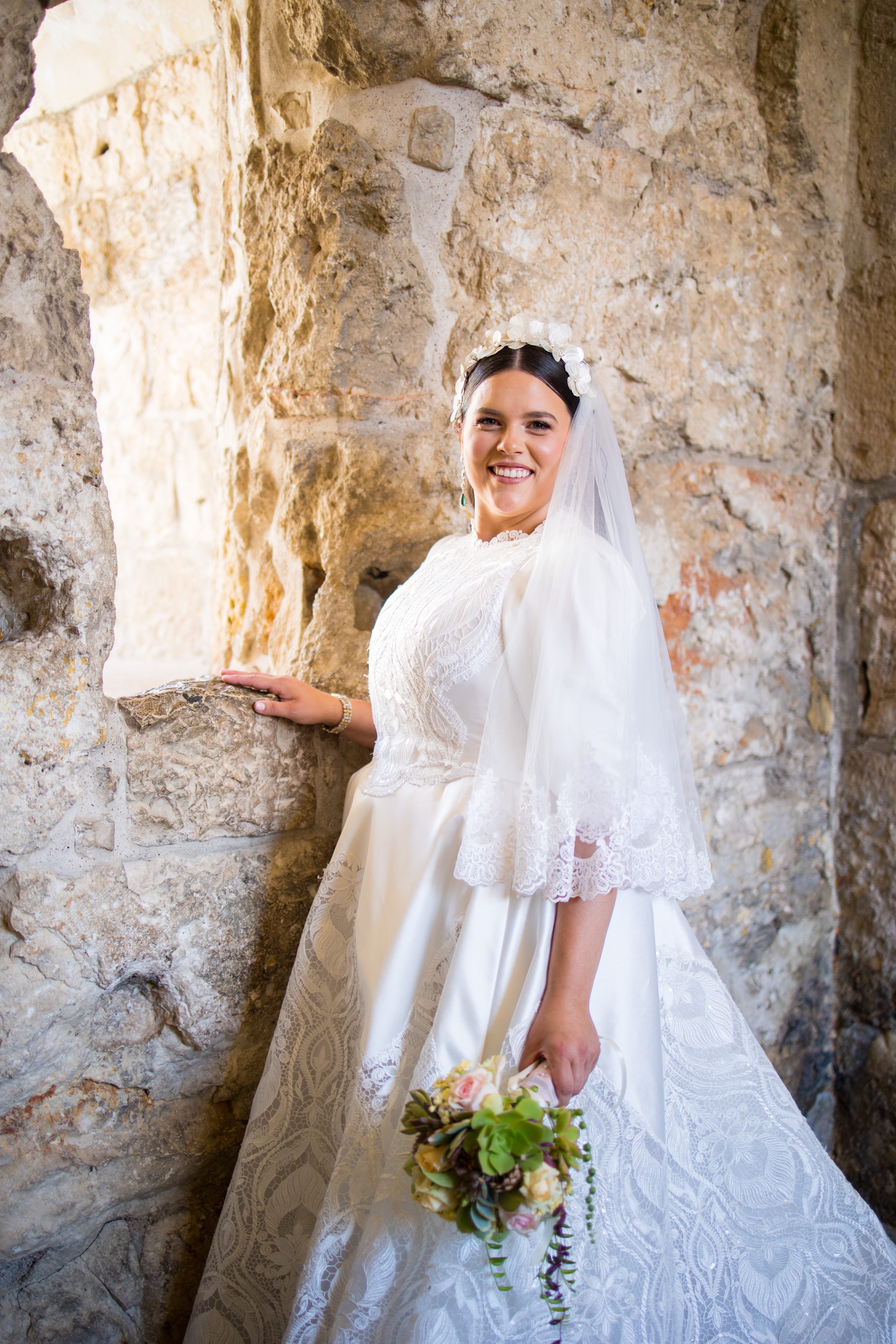 A bride with her bouquet in a stone passage